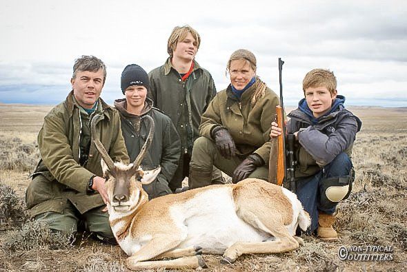 Family posing with a harvested pronghorn antelope in a field.