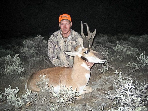 A man in a camo jacket is posing with a deer