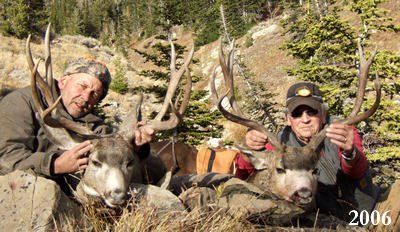 Two men pose with large mule deer bucks they have harvested outdoors in 2006.