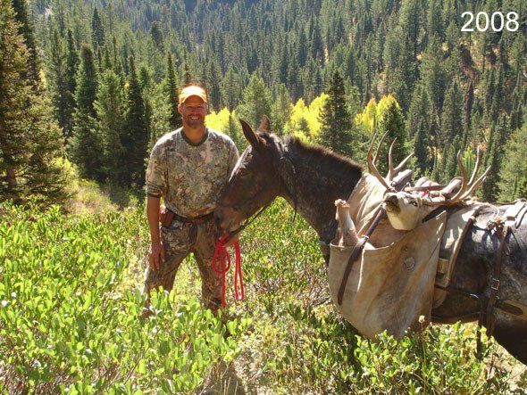 Hunter in camo with a pack mule carrying an animal, standing in a forest setting in 2008.