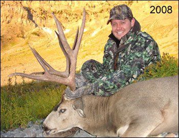 Hunter in camouflage with large-antlered deer, smiling. Yellow backdrop, labeled 2008.