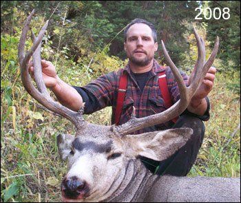 Man kneeling with deer he harvested; holding antlers; 2008.
