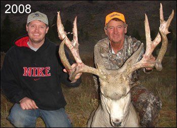 Two men holding a large buck with massive antlers, outdoors at dusk, 2008.