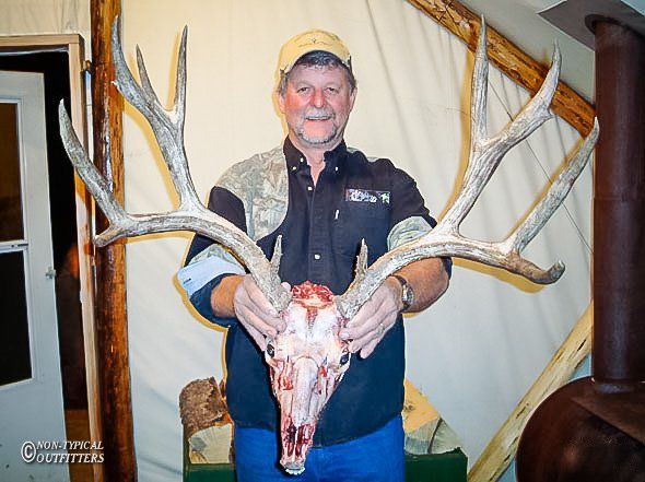 A man holding a large deer skull with antlers