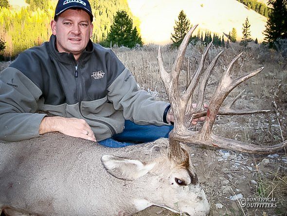 A man in a north face jacket is posing with a deer