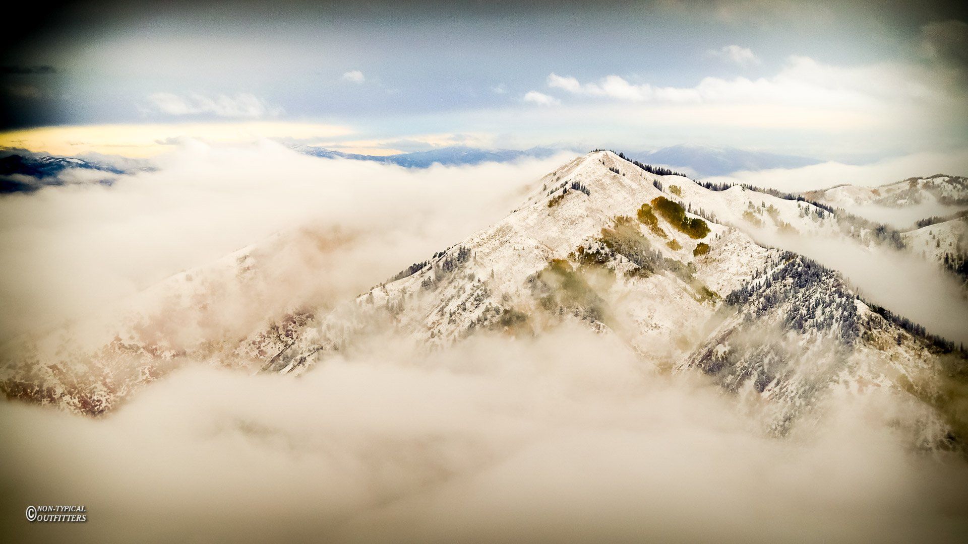 A mountain covered in snow is surrounded by clouds