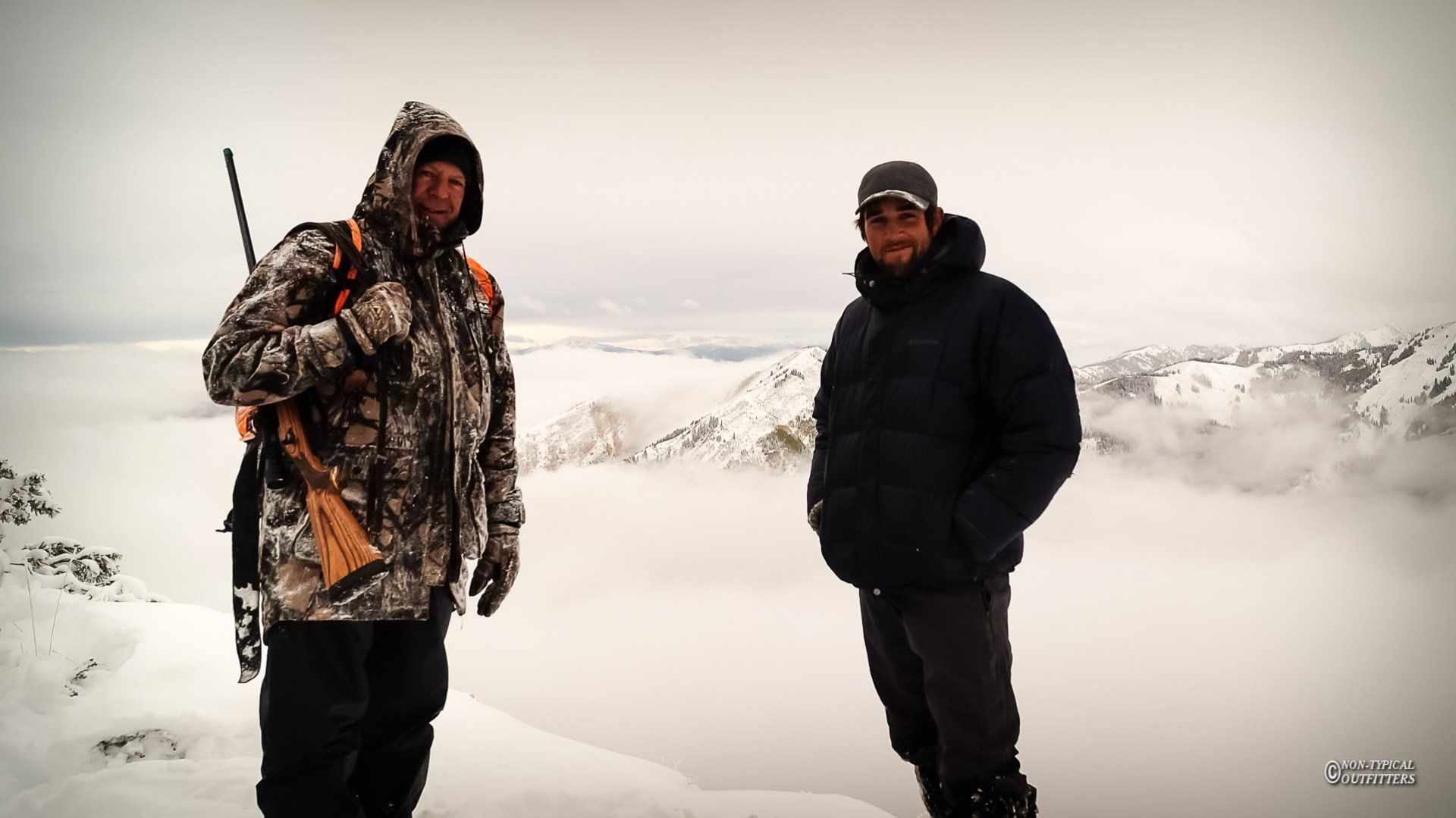 Two men standing on top of a snow covered mountain