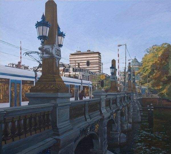 Een tram rijdt over een sierlijke stenen brug in Amsterdam, met klassieke lantaarnpalen, een gracht en herfstbomen.