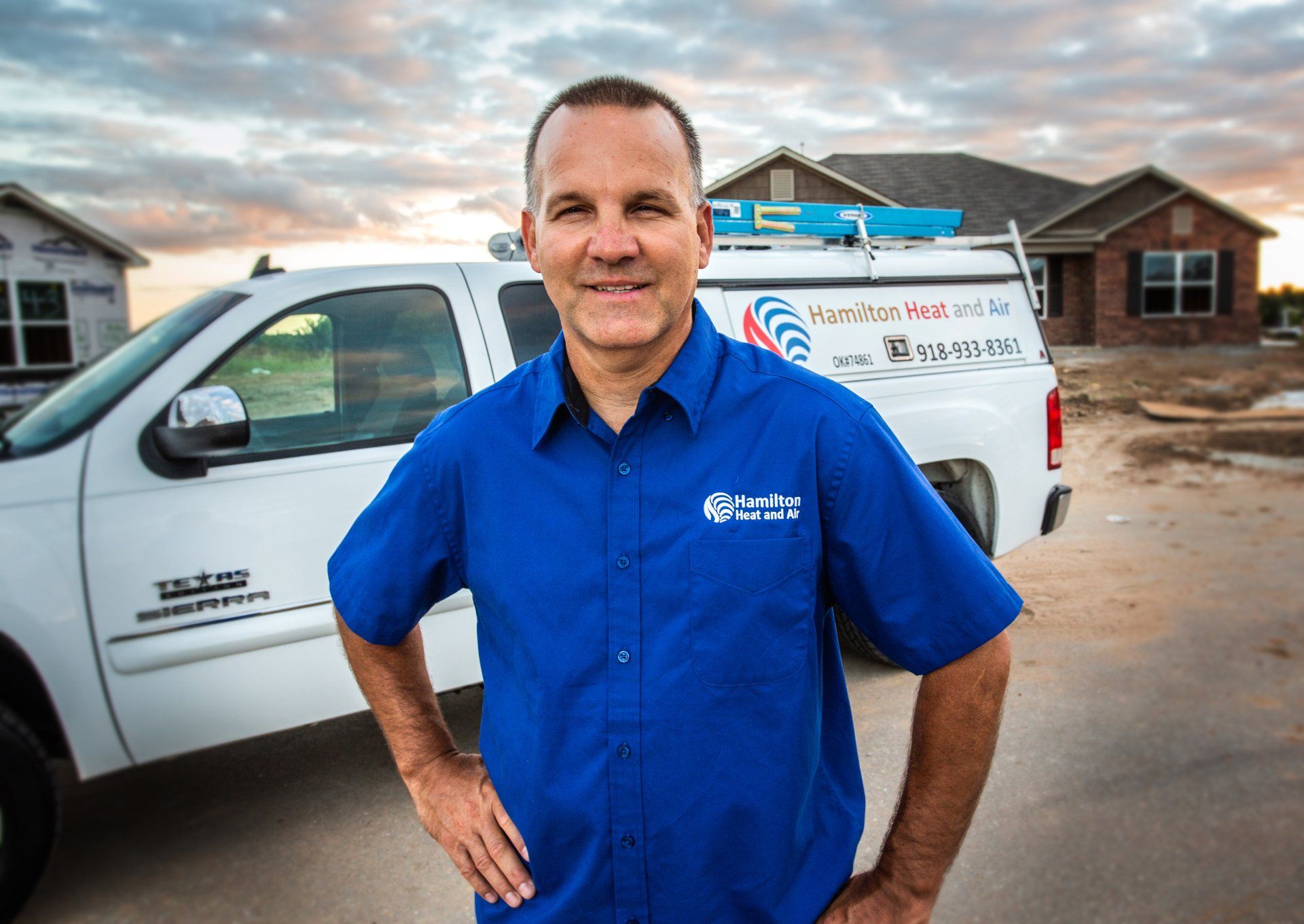 A man in a blue shirt is standing in front of a white truck.