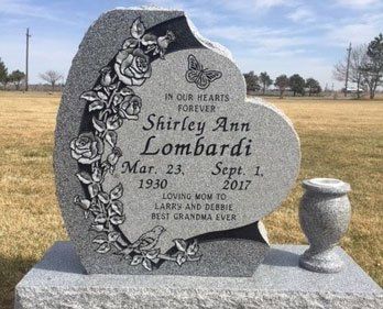 Gray heart-shaped headstone with floral design and text: