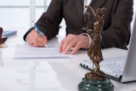 ein Mann an seinem Schreibtisch und eine Statue mit einer Waage