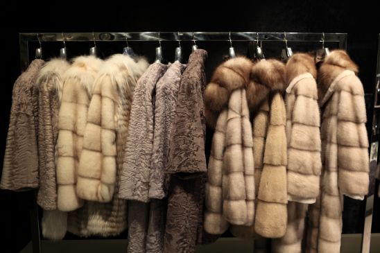 Una fila di pellicce appese a uno stendino, nei toni neutri del beige e del marrone.