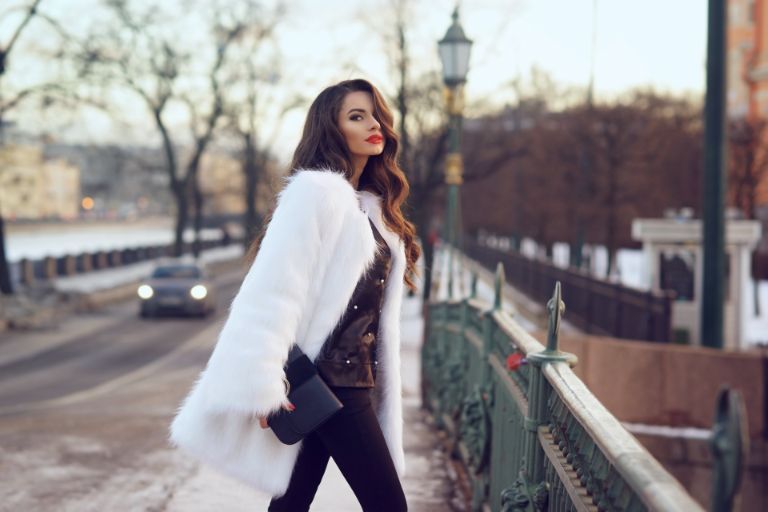 Una donna in camice bianco cammina lungo un ponte accanto a una strada al crepuscolo.