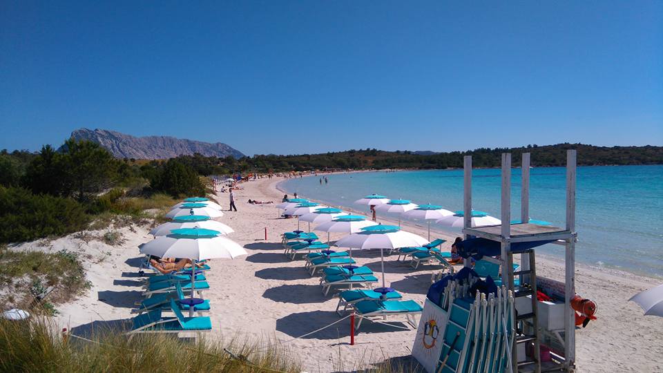 spiaggia con sdraio e ombrelloni bianchi e azzurri