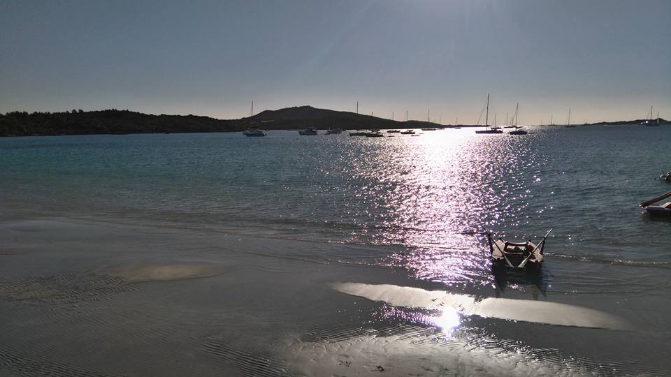 spiaggia con piccole imbarcazioni in lontananza