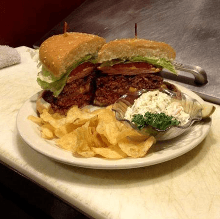 Large sandwich with chips and a side of creamy dip on a white plate