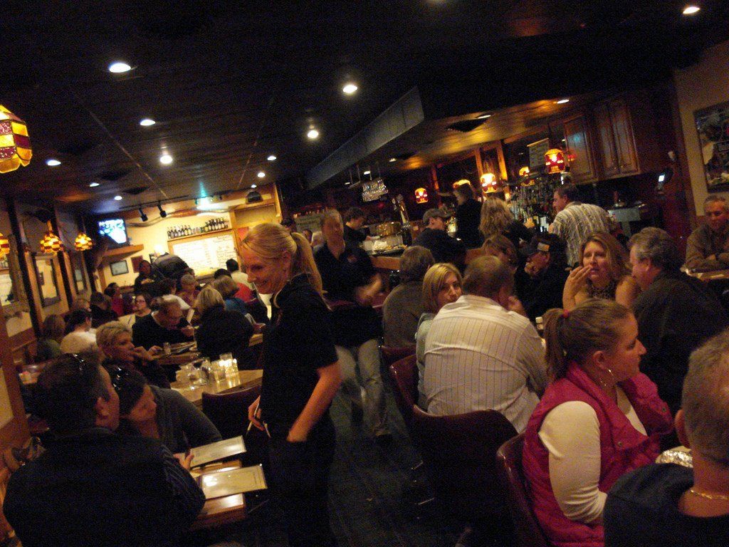 Crowded restaurant with diners seated at tables in a warm, dimly lit interior