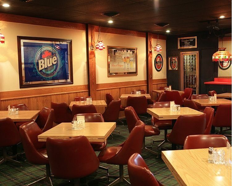 Empty cozy pub interior with red chairs, wooden tables, and beer signs on the walls