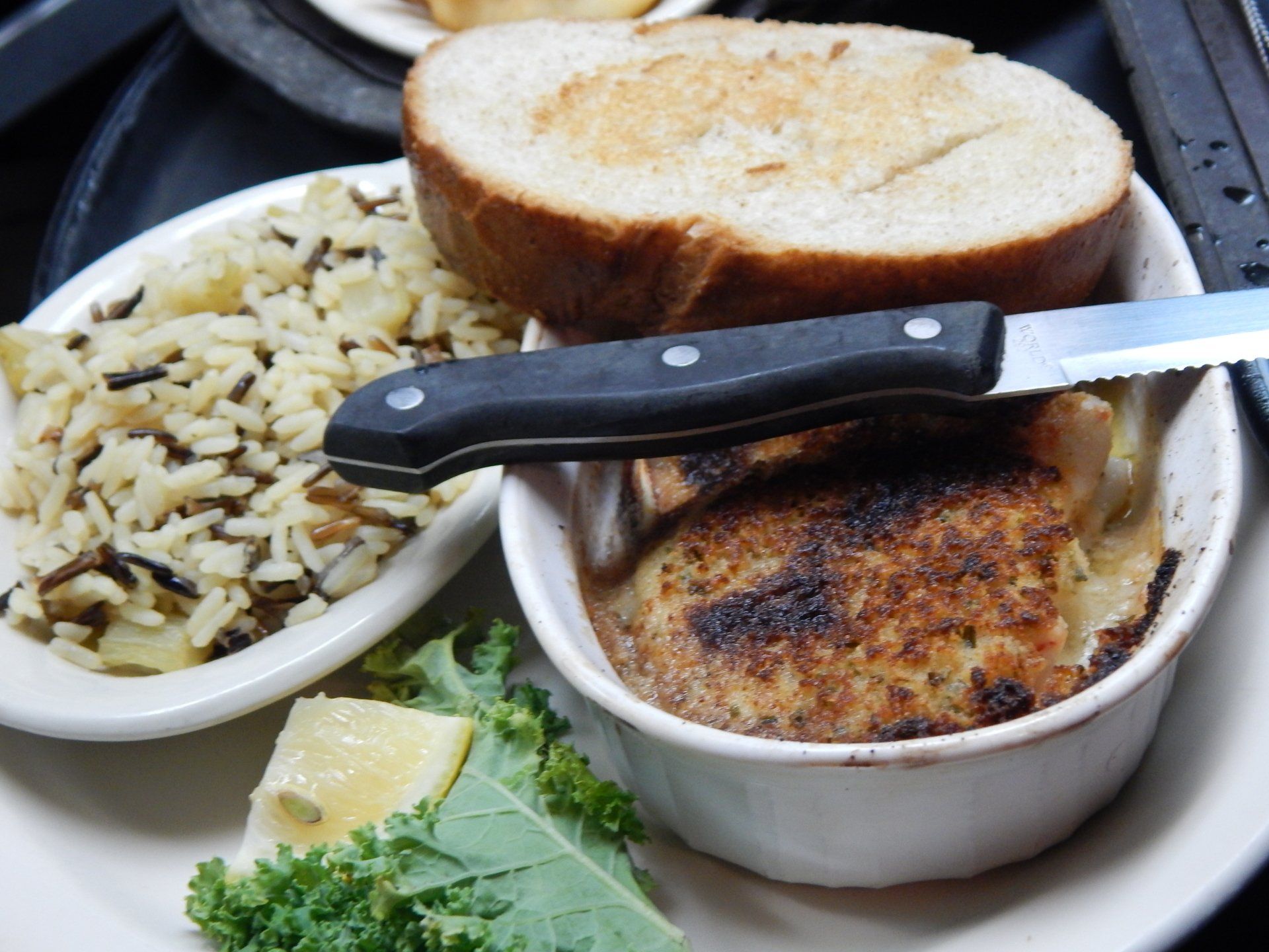 Plate with sliced bread, rice, and a small baked dish with a knife on top