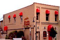 Brick building with red awnings on windows and entrance, viewed from the street