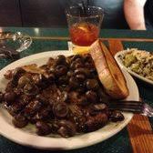 Plate of dark cooked shellfish with bread, rice side dish, and a drink on a restaurant table