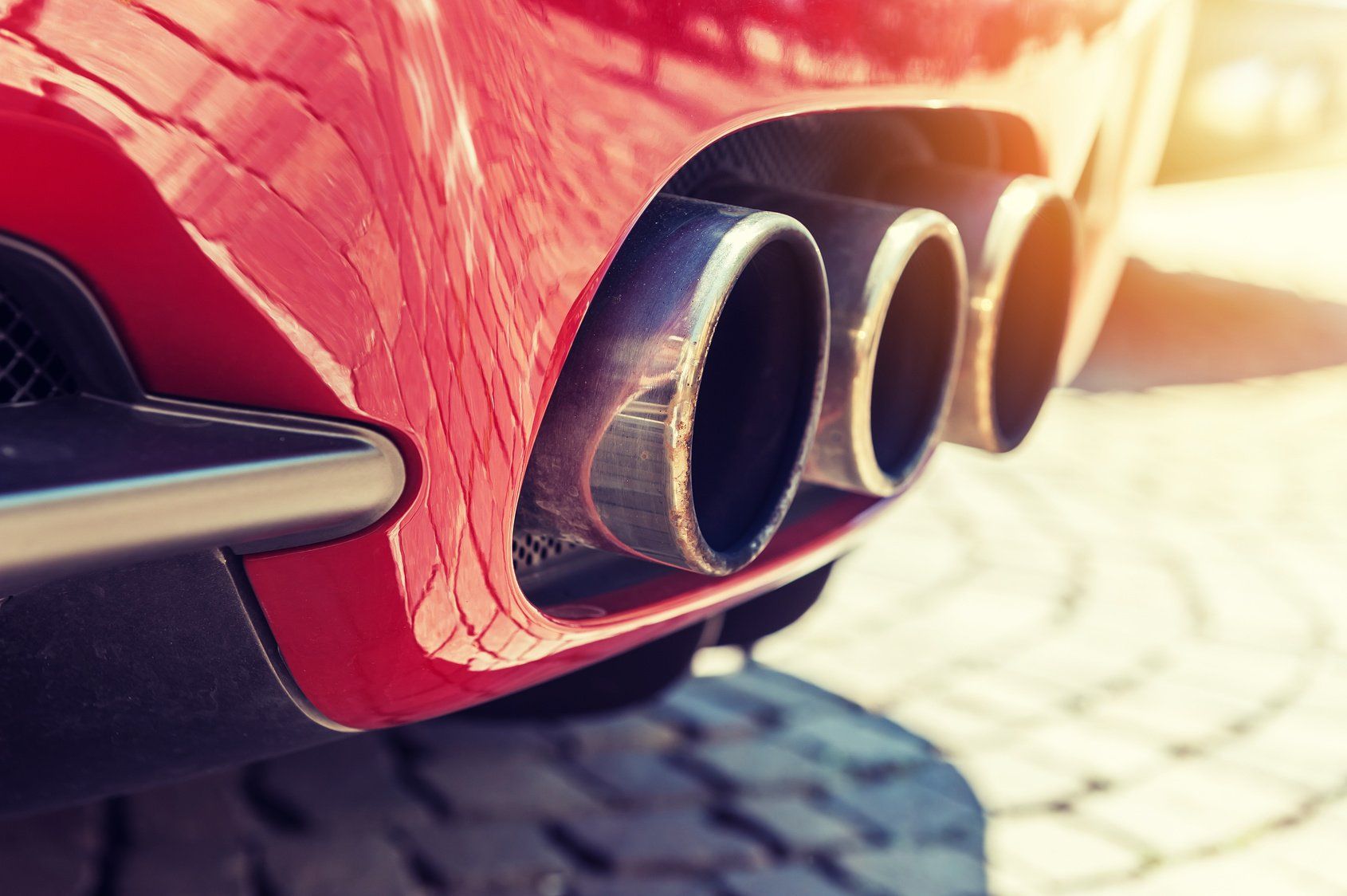 The exhaust pipes of a red sports car are visible.