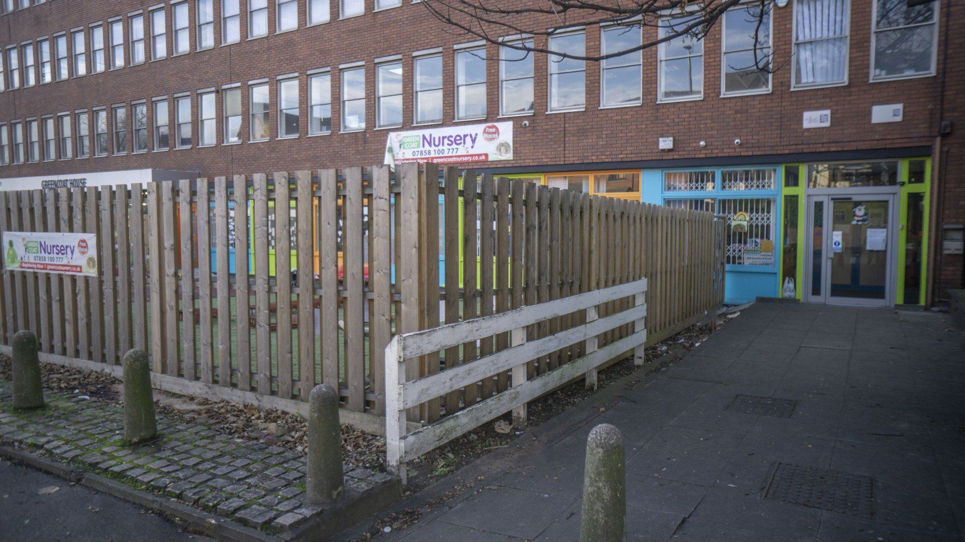 Exterior of a daycare center with a wooden fence and a colorful sign.