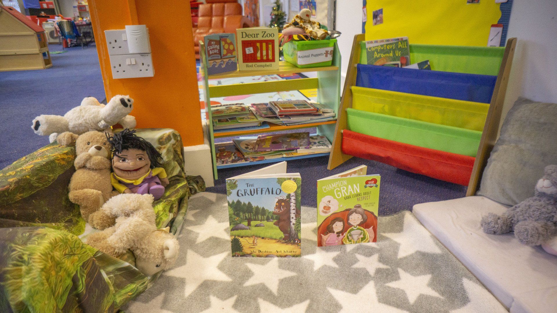 Reading corner with books, stuffed animals, and colorful bookshelves.