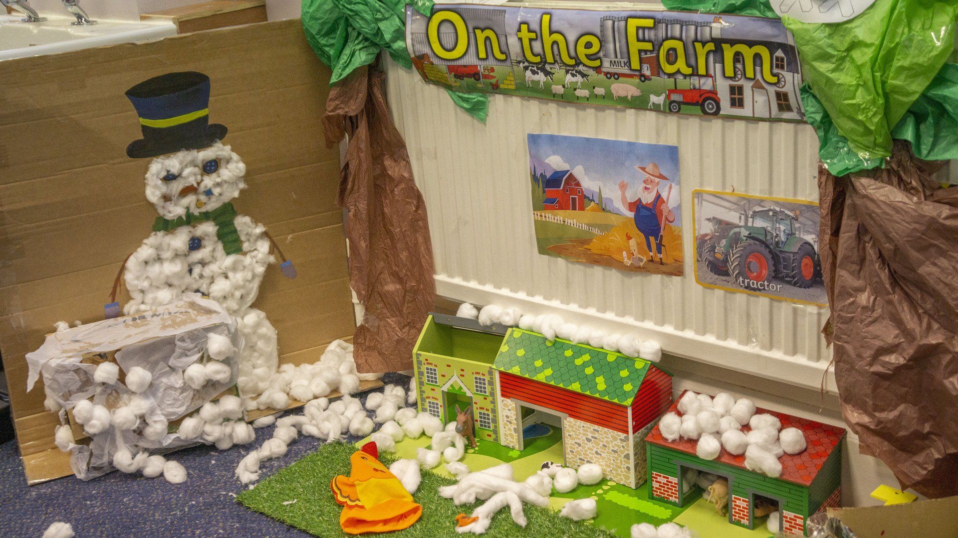 Children's farm-themed craft project with paper barns, snowman, tractor, and cotton balls.