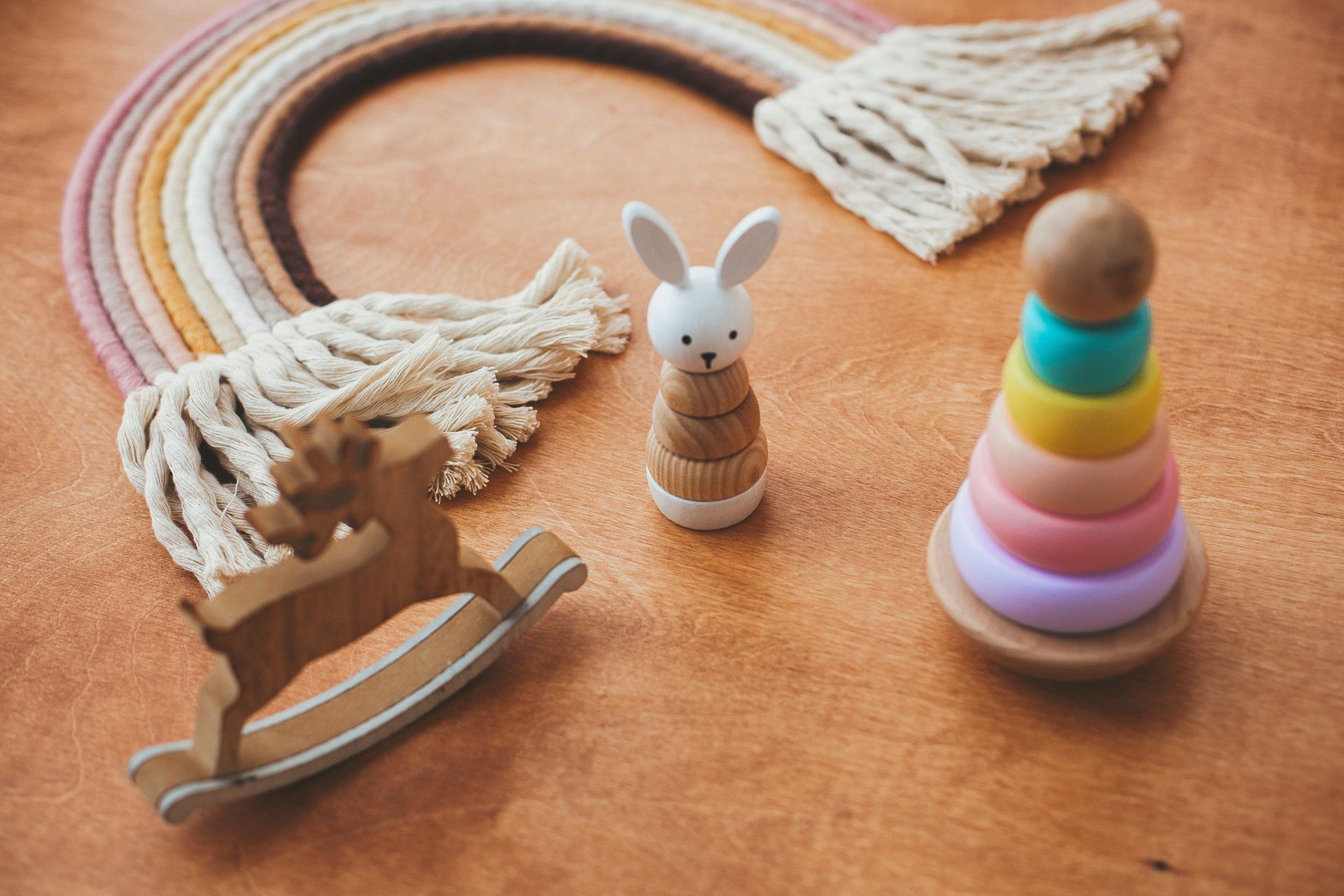 Wooden toys: rocking deer, bunny stacker, ring stacker, with a rainbow decoration.