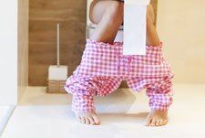 woman sitting on toilet with toilet paper in hand