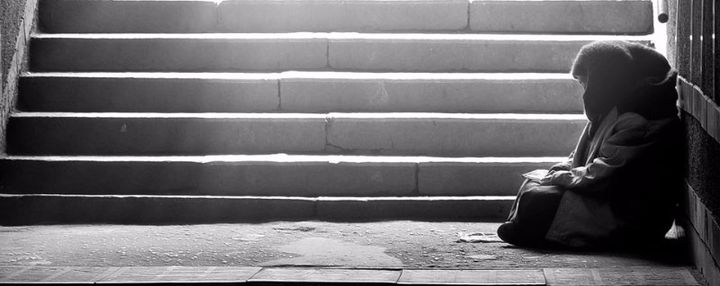 monochrome photo of homeless woman reading a book at the subway entrance