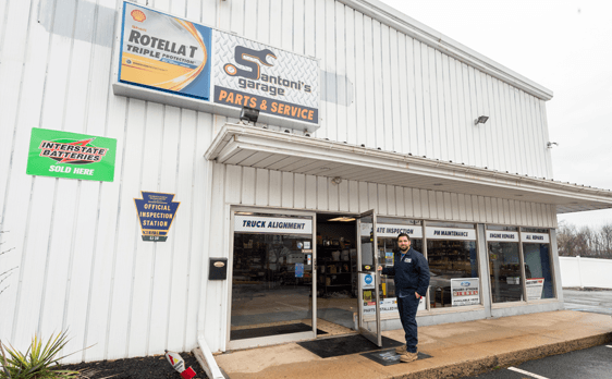 A person stands at the entrance of a garage. The building has a sign saying