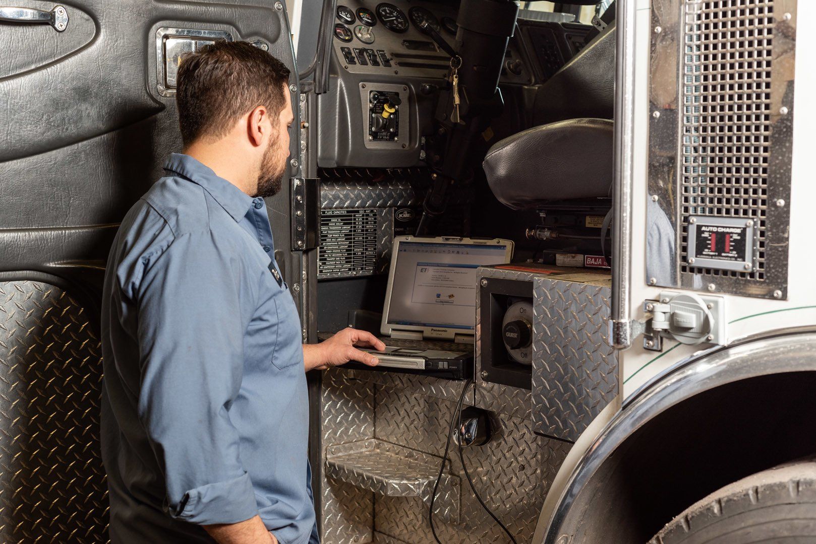 Mechanic using laptop inside a fire truck cab.