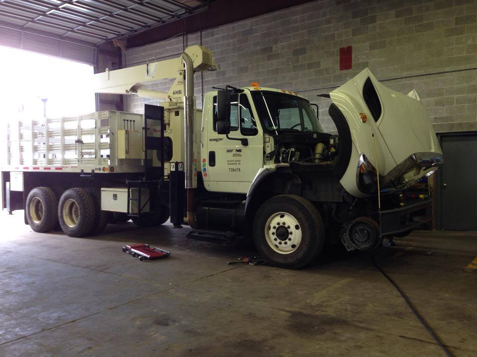 White truck with open hood inside a garage.