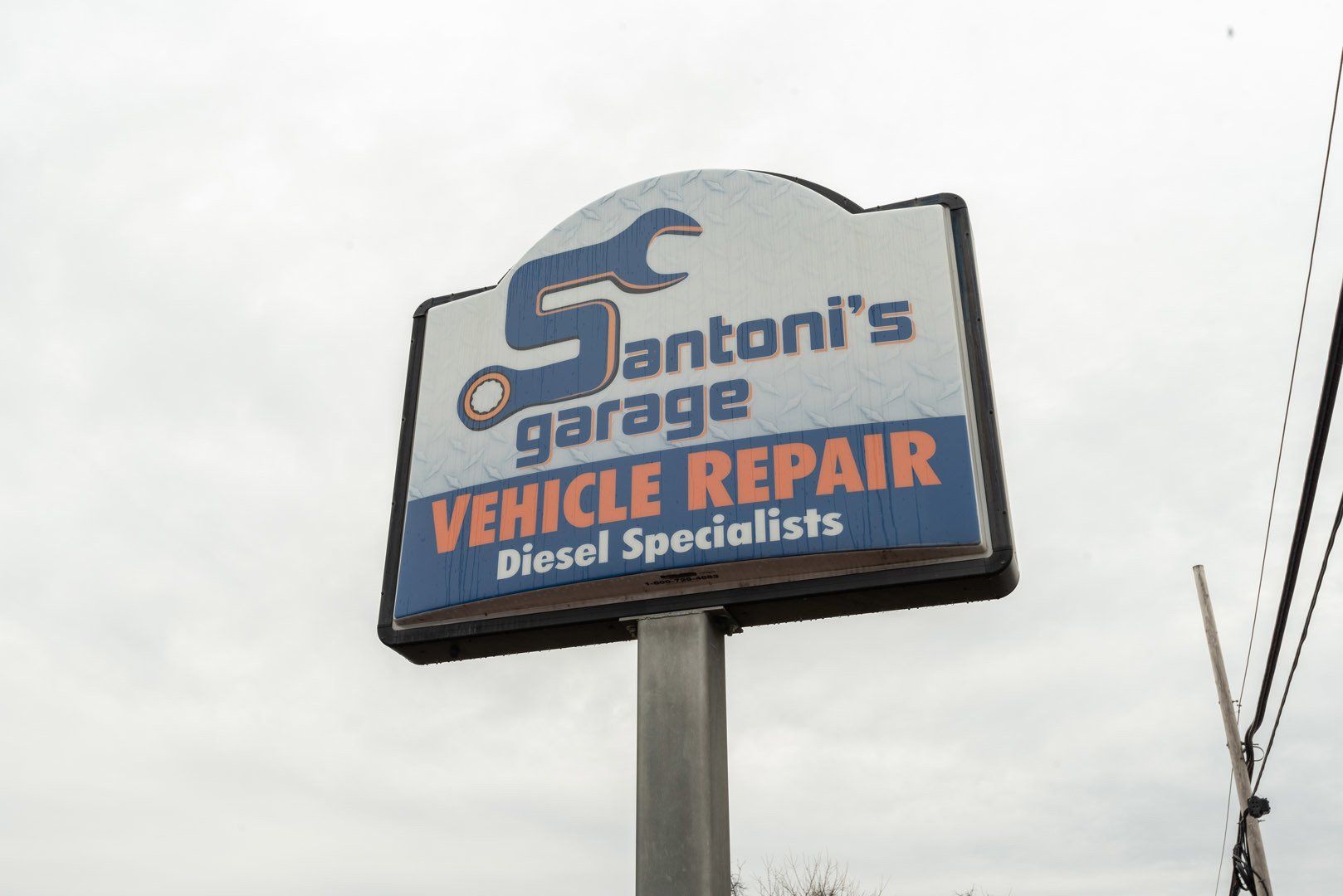 Sign for Santoni's garage, a vehicle repair shop with diesel specialists. Blue, white, and orange.