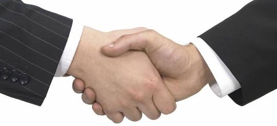 Due uomini in giacca e cravatta si stringono la mano su uno sfondo bianco