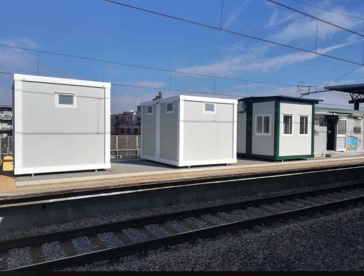 Una fila di edifici bianchi si trova accanto a un binario ferroviario.