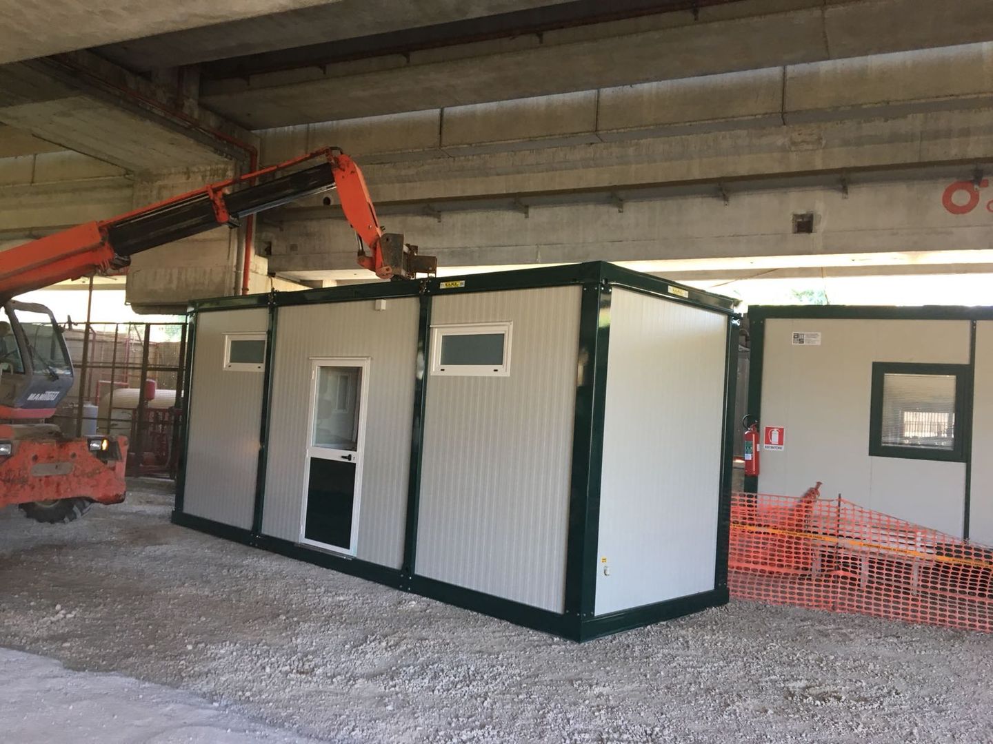 Una gru sta sollevando un container in un edificio.