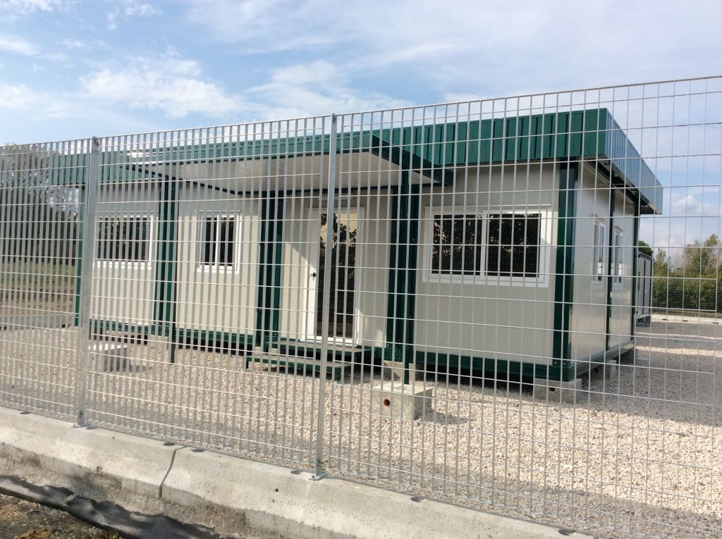 Dietro una recinzione si trova un edificio con tetto verde.