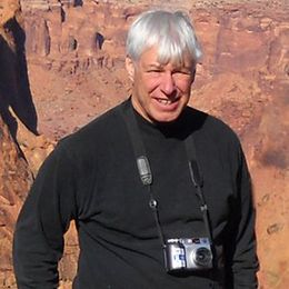 A man wearing a black shirt and a camera around his neck