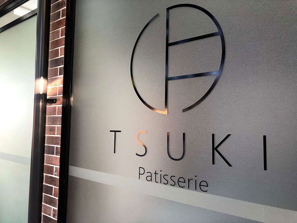 Black Painted Logo On Glass Panel — Signage In Acacia Ridge, QLD