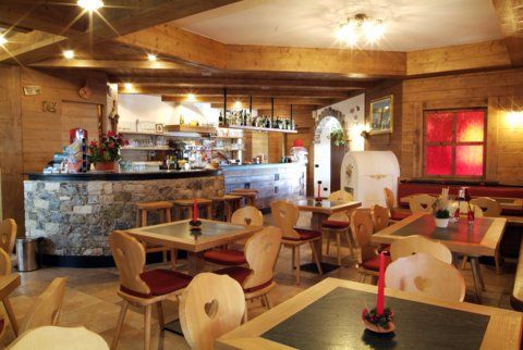 Accogliente ristorante con interni in legno, bar, tavoli e sedie. Alcuni clienti sono seduti.