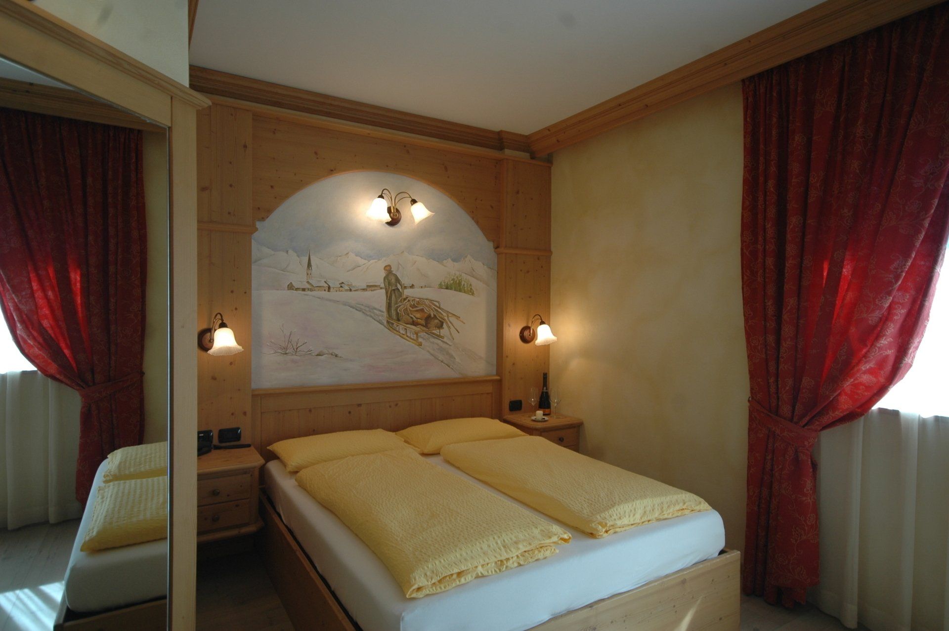 Camera da letto con letto matrimoniale, mobili in legno, tende rosse e un murale.