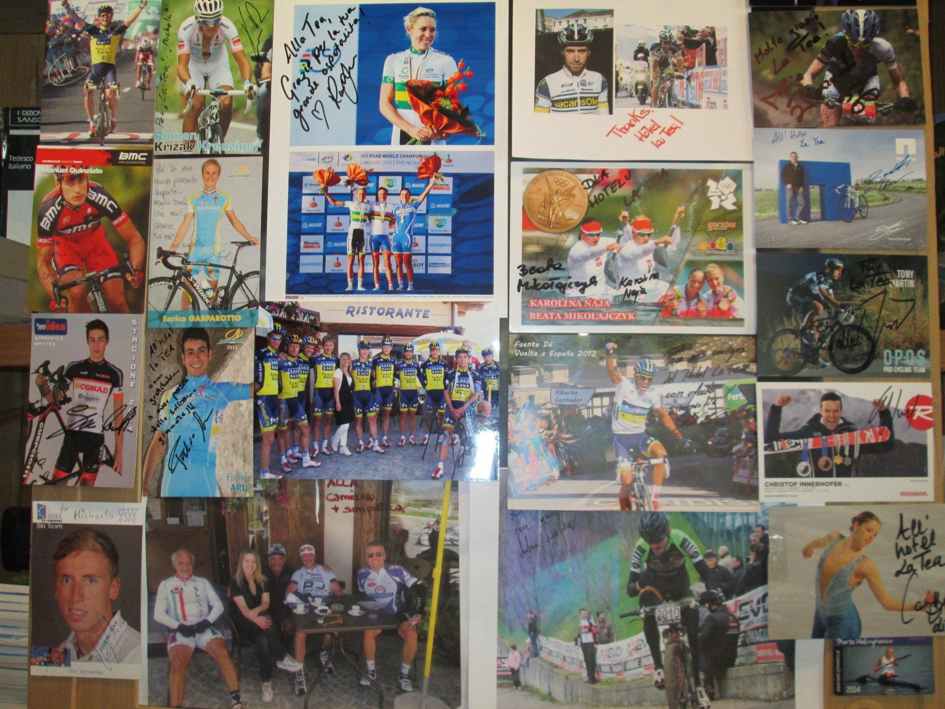 Esposizione a parete di foto e cimeli del ciclismo raffiguranti ciclisti, squadre e scene di gara.