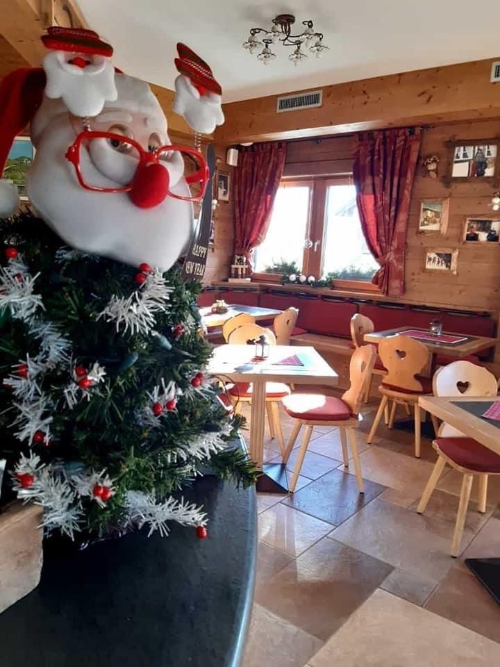 Decorazione di Babbo Natale accanto all'albero di Natale all'interno di un accogliente ristorante con pareti in legno.