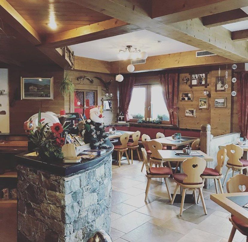Accogliente ristorante con tavoli e sedie in legno, bancone in pietra e dettagli rossi.