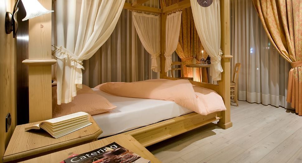 Accogliente camera da letto con letto a baldacchino, tende e comodini, caratterizzata da tonalità pesca e beige.