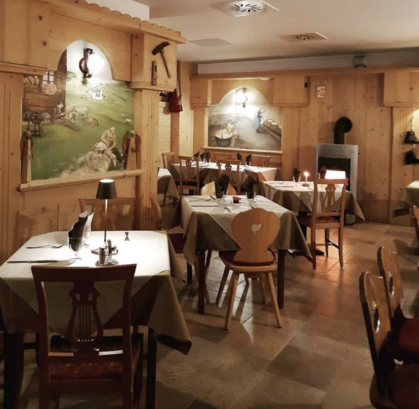 Accogliente ristorante con interni rivestiti in legno, tavoli apparecchiati con posate e un murale sulla parete.