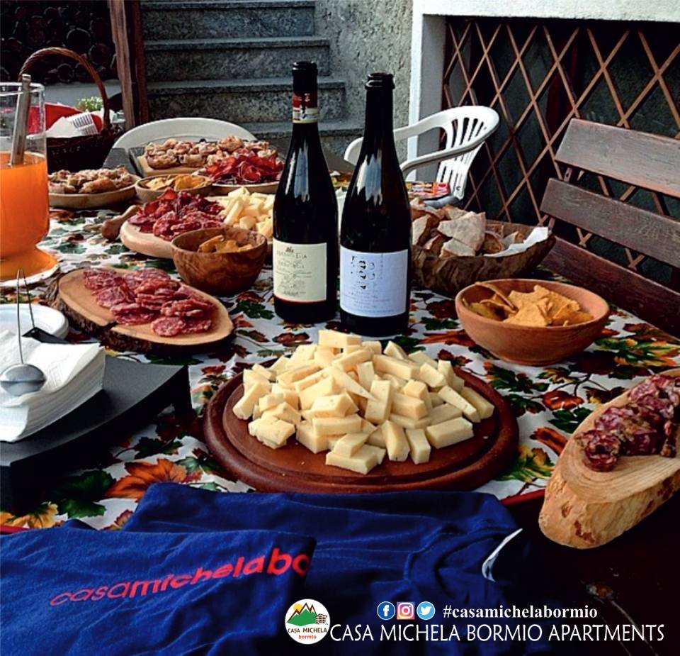 Tavolo con cibo e vino all'aperto con una maglietta blu con la scritta